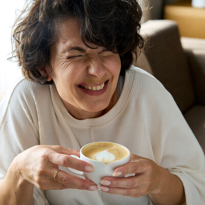 Lachende Dame mit Kaffee im 4 Sterne Stadthotel Henriette - ehemals Hotel Capri - in Wien.