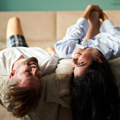 Laughing couple in a double bed at the Boutique Hotel Henriette in Vienna.