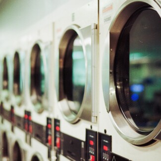 A row of industrial washing machines in a laundromat, emphasizing cleanliness and efficiency.