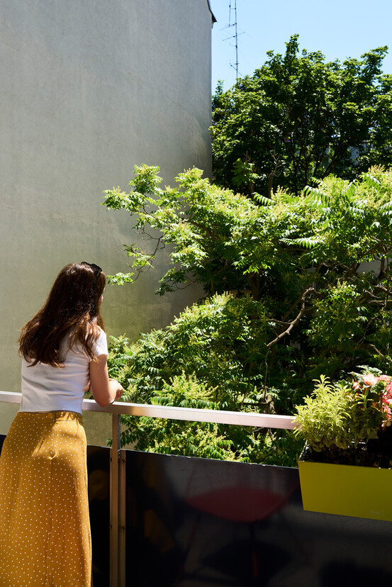 Lady on the balcony overlooking the trees in front of the Henriette Stadthotel near the Messe Wien Exhibition & Congress Center.