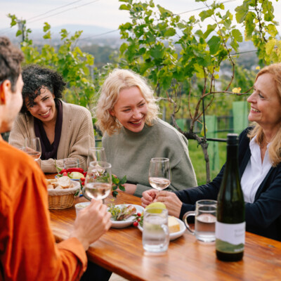 Eine Gruppe von Menschen genießt ein Essen im Freien mit Wein am Nussberg.