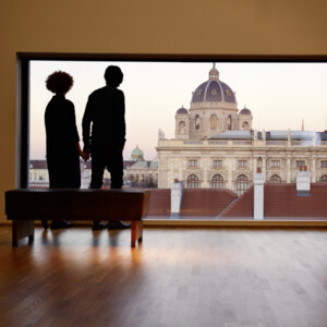 Pärchen blickt vom Panoramafenster des Leopoldmuseums im MQ auf das Kunsthistorische Museum in Wien