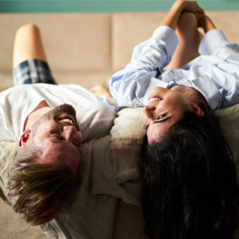 A smiling couple relaxes on a cozy double bed at Stadthotel Henriette Vienna.