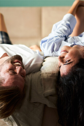 A smiling couple relaxes on a cozy double bed at Stadthotel Henriette Vienna.