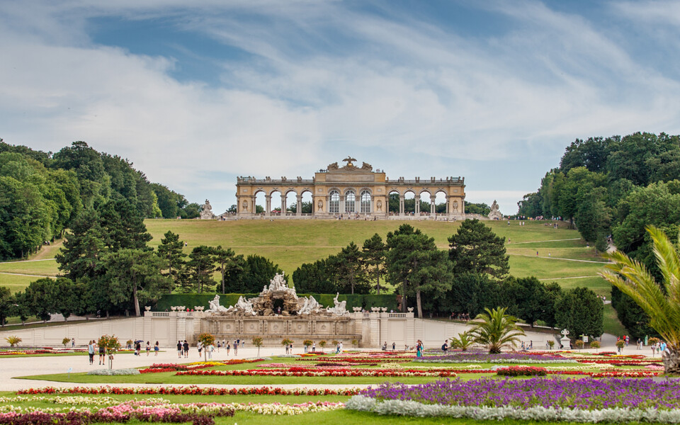Enjoy spring in Vienna with 13% off: the Gloriette at Schönbrunn Palace above colorful spring flowerbeds in the Palace park.