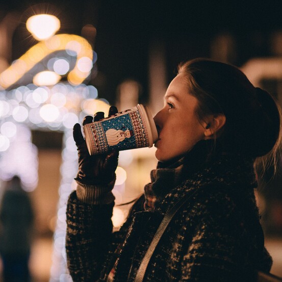 Junge Dame mit einem Punsch auf einem der zahlreichen Christkindlmärkte in Wien.