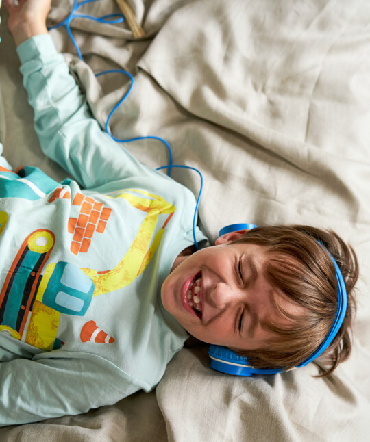 Ein Kind hört Musik während es am Bett liegt