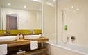 Großes Badezimmer mit Badewanne und Doppelwaschbecken in einer Familiensuite im Hotel Henriette, Wien.