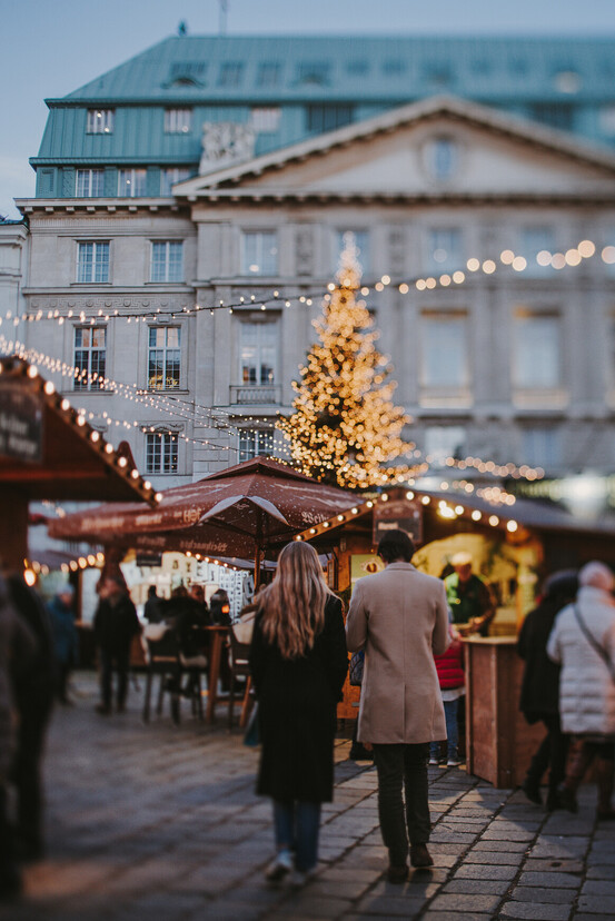 Couple strolling through the romantic Christmas market on Stephansplatz in Vienna.