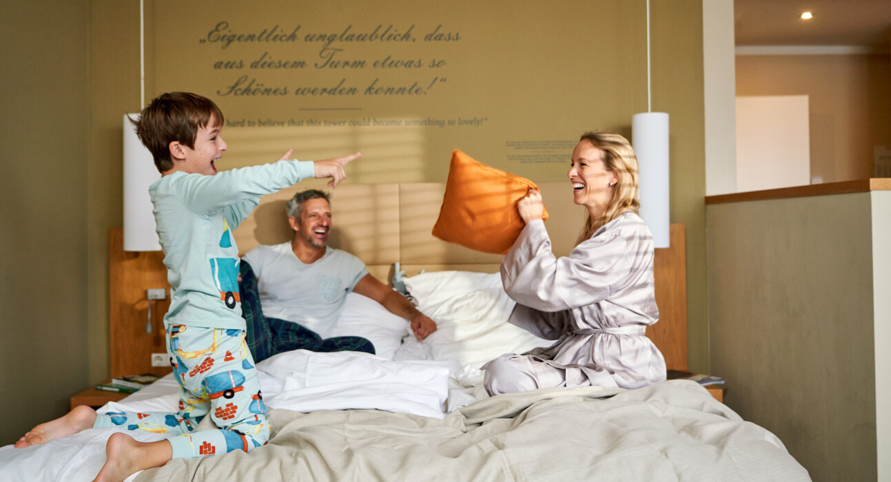 Eine Familie im Bett kuschelnd im gemütlichen Bett im Familienzimmer der Henriette