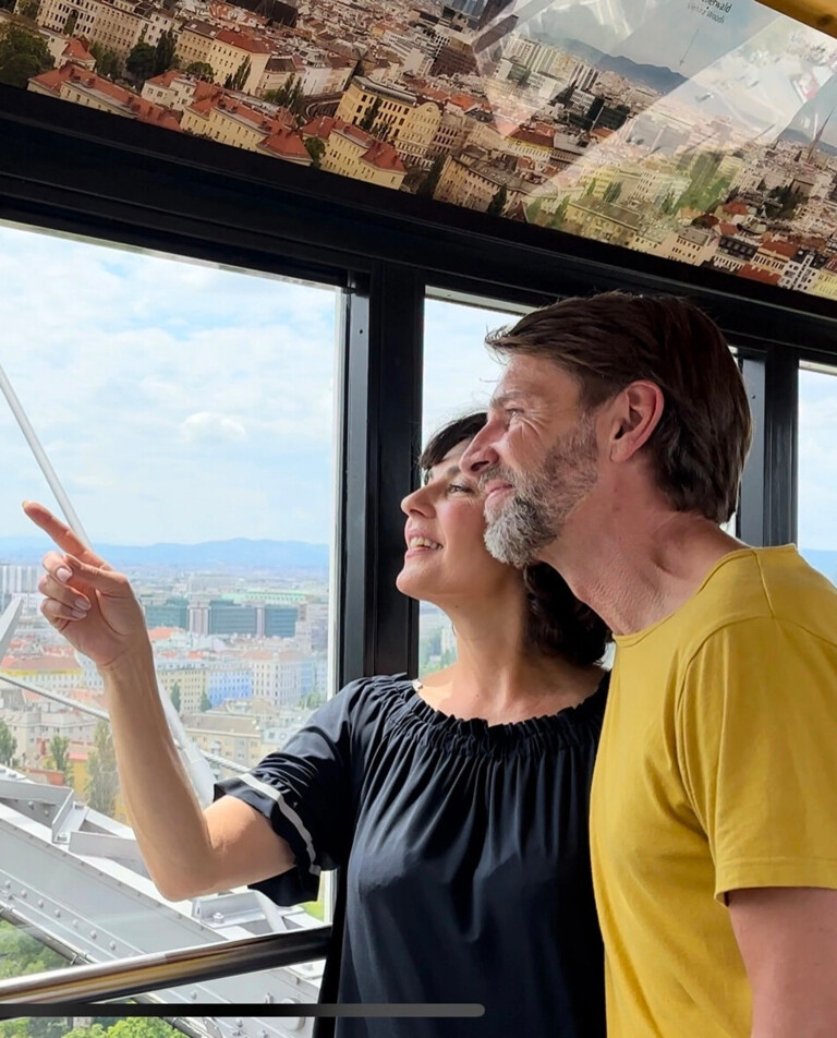 Couple in a gondola of the Giant Ferris Wheel discovering Vienna from above.