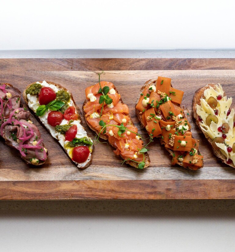 A wooden board displaying assorted gourmet bruschetta with diverse toppings, showcasing a variety of flavors and vibrant colors.
