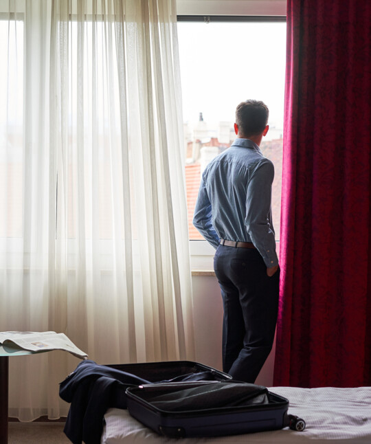 Ein Business-Reisender blickt in seinem Hotelzimmer aus dem Fenster