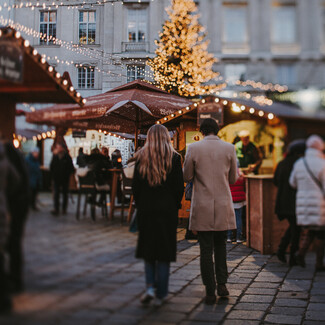 Pärchen beim Flanieren über den romantischen Weihnachtsmarkt am Stephansplatz in Wien.