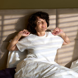 Woman stretches after waking up in Henriette's cosy hotel room
