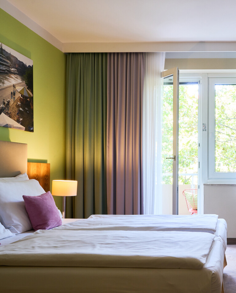 Großes Doppelzimmer mit Sitzgelegenheit und Balkon im Henriette Stadthotel in der Wiener Innenstadt.