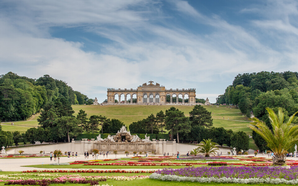 Mit dem 13 % Winter Special Frühlingserwachen in Wien genießen: die Gloriette des Schloss Schönbrunn über den bunten Blumenbeeten des Schlossparks im Frühling.