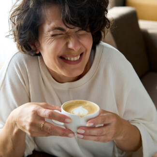 Lachende Dame mit Kaffee im 4 Sterne Stadthotel Henriette in der Wiener Innenstadt.