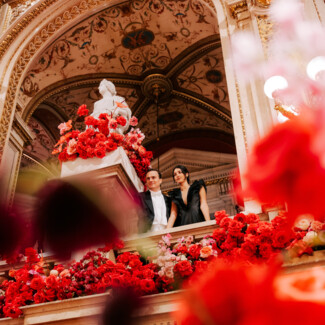 Two ball guests at the Vienna Opera Ball in the flower-adorned State Opera.