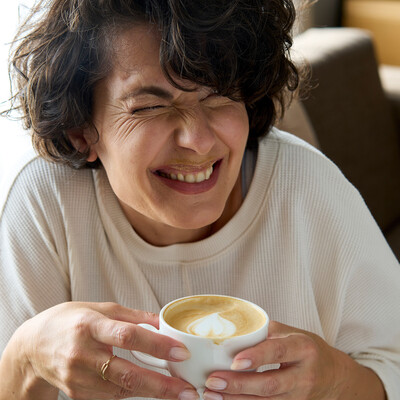 Lachende Dame mit Kaffee im 4 Sterne Stadthotel Henriette in der Wiener Innenstadt.