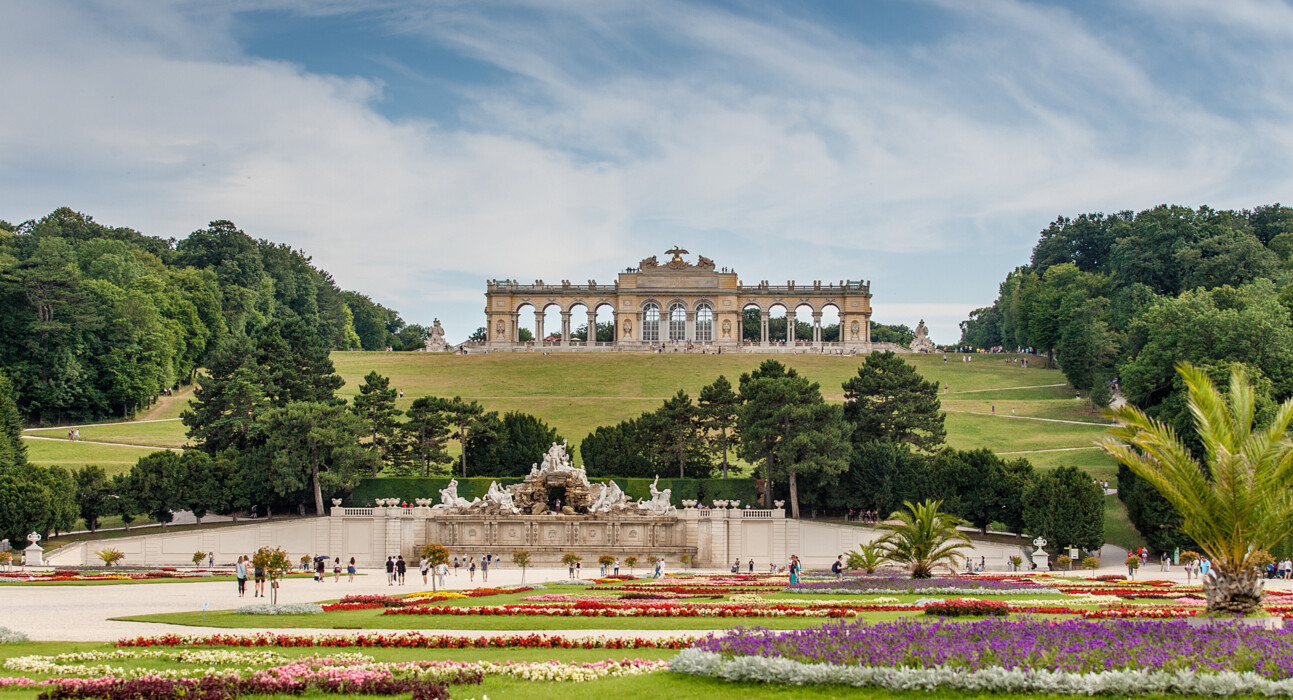 Mit dem 13 % Winter Special Frühlingserwachen in Wien genießen: die Gloriette des Schloss Schönbrunn über den bunten Blumenbeeten des Schlossparks im Frühling.