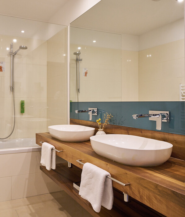 Modern bathroom with double sinks and tub at the Henriette City Hotel in Vienna.