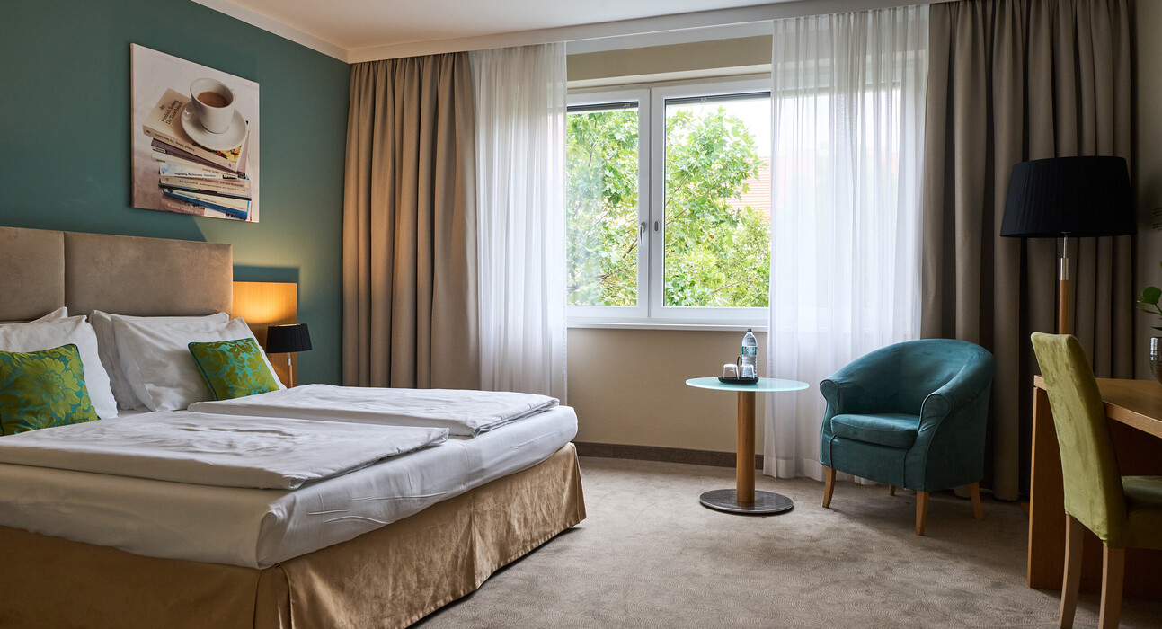 Großzügiges Doppelzimmer mit Doppelbett und Blick ins Grüne im 4* Hotel Henriette in Wien.