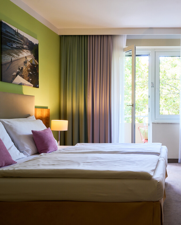 Großes Doppelzimmer mit Sitzgelegenheit und Balkon im Henriette Stadthotel in der Wiener Innenstadt.