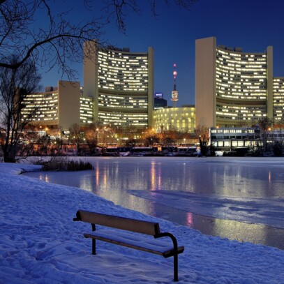 The brightly lit Vienna International Centre against a snowy backdrop.