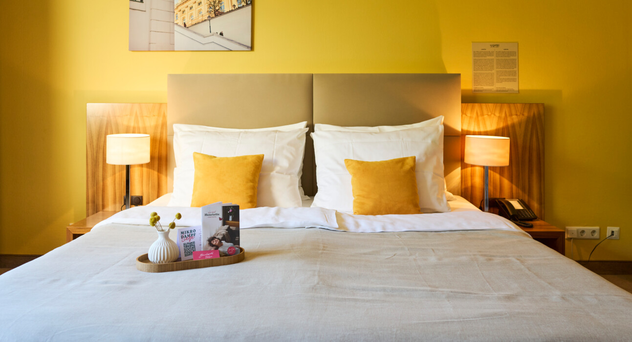 Large bed with organic bedding for a restful sleeping experience at Henriette City Hotel