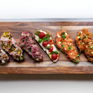 A wooden board displaying assorted gourmet bruschetta with diverse toppings, showcasing a variety of flavors and vibrant colors.