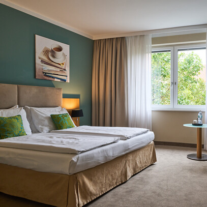Großzügiges Doppelzimmer mit Doppelbett und Blick ins Grüne im 4* Hotel Henriette in Wien.