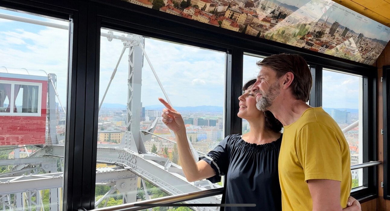 Couple in a gondola of the Giant Ferris Wheel discovering Vienna from above.