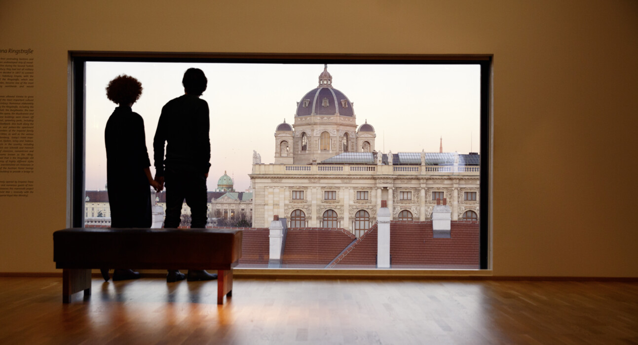 Pärchen blickt vom Panoramafenster des Leopoldmuseums im MQ auf das Kunsthistorische Museum in Wien.